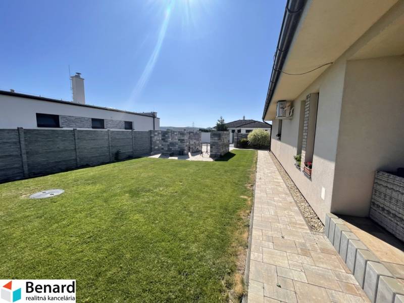 A family house in Prešov with a lawn and a paved walkway in a sunny yard.