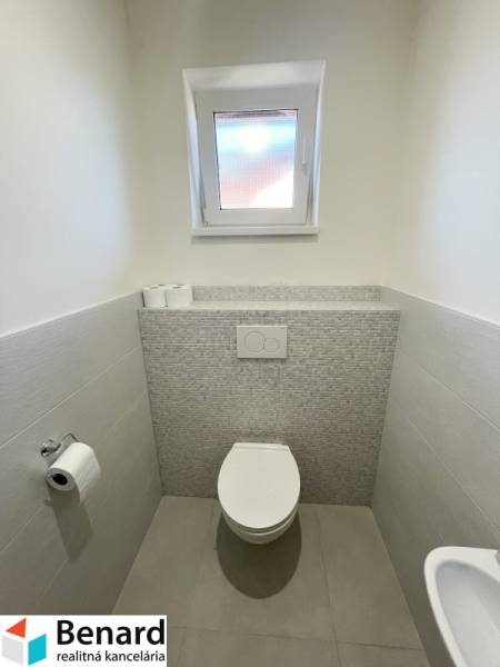 Bathroom in a family house with ceramic tiles and a toilet.