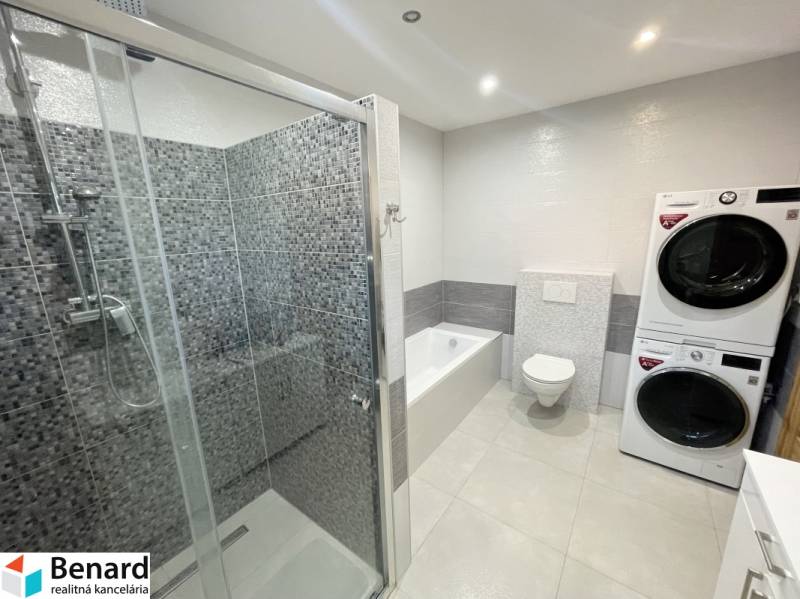 A bathroom in a family house with a bathtub, shower, and a washer with a dryer.