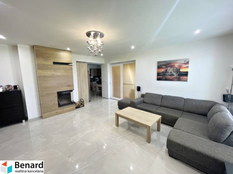 Living room in a family house with a gray sofa, fireplace, and pendant light.