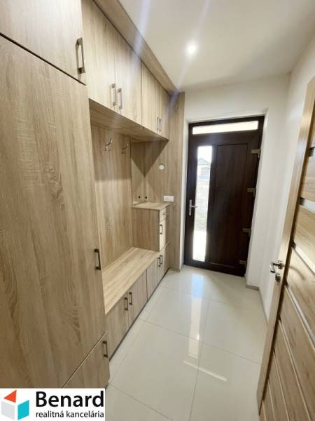 Entrance hall with wooden furniture in a family house, includes storage space and entrance doors.