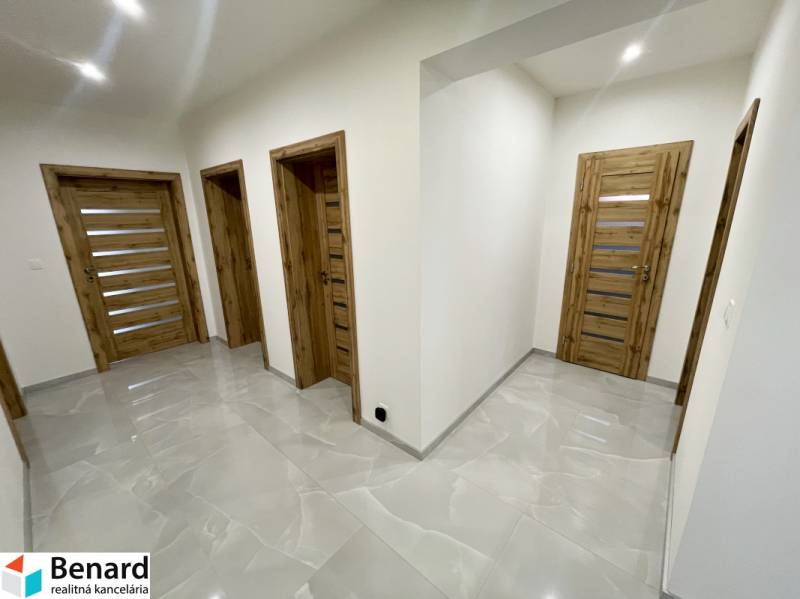 A hallway in a family house with wooden doors and glossy tiles.