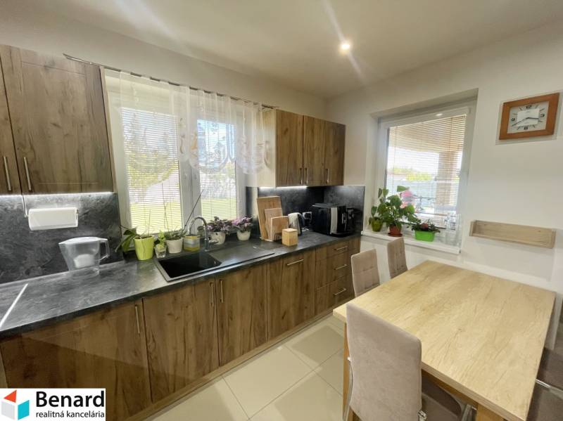 A kitchen in a family house with wooden cabinets and a dining table.