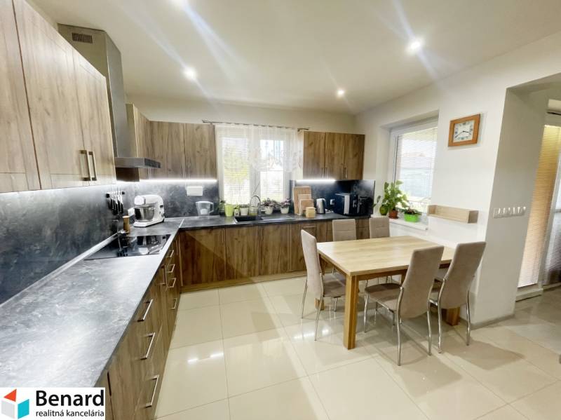 A kitchen in a family house with built-in appliances and a dining table for six people.