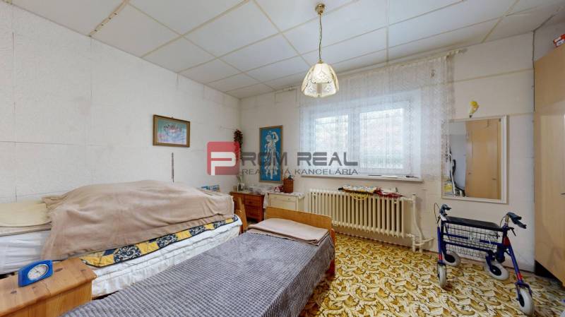 Room with a bed, carpet, and walker in a family house.