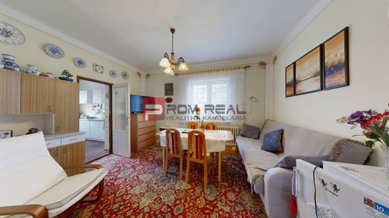 Living room in a family house with a sofa, dining table, and wall decorations.