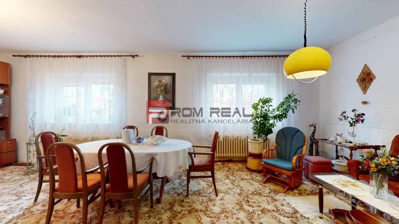 Living room in a family house with a table, chairs, decorations, and a yellow lamp on the ceiling.