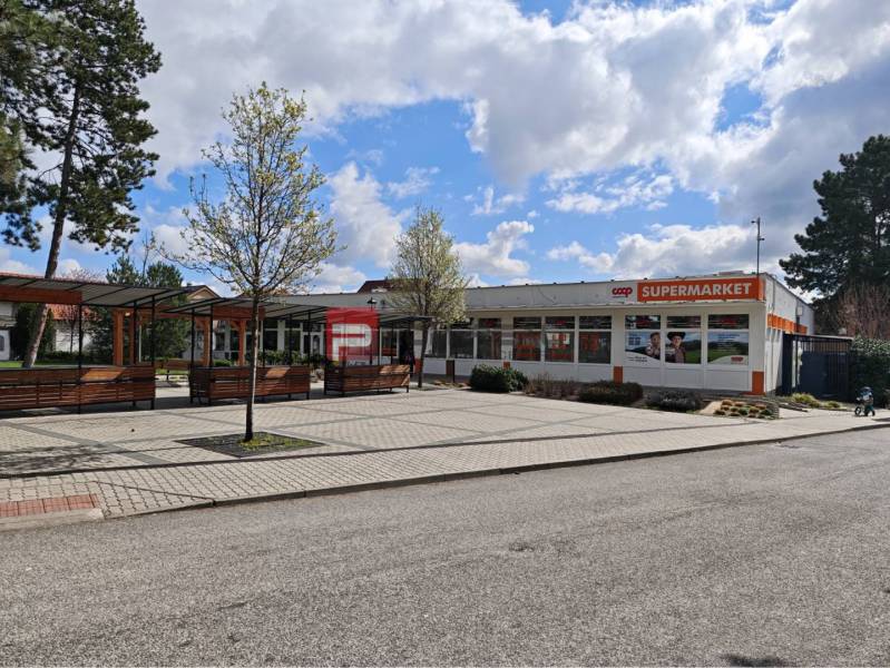 Commercial premises on Partizanska Street in Svätý Jur with a supermarket, benches, and trees.
