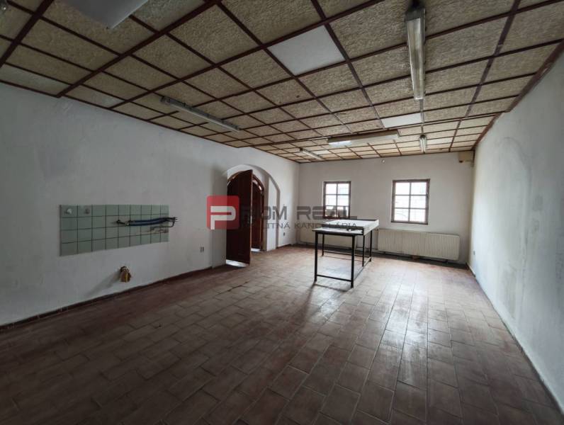 An empty interior of commercial premises with a tiled wall and skylights.