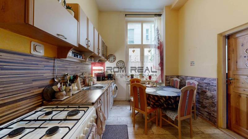 A kitchen with a dining table in a 2-room apartment, light walls, and wooden cabinets.
