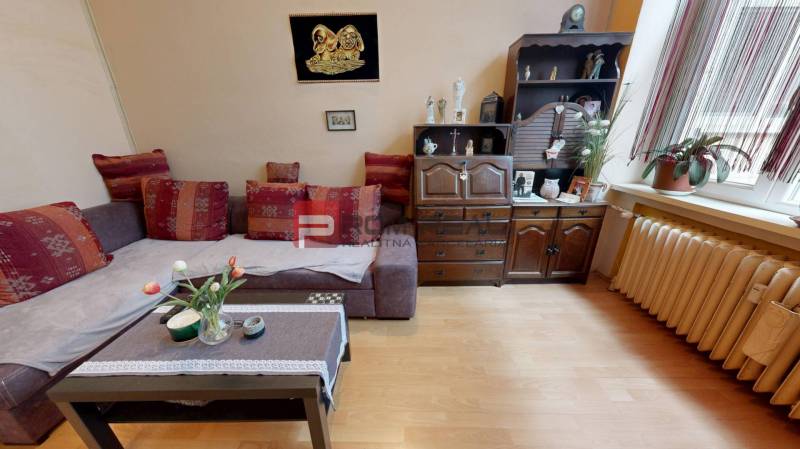 A living room with a sofa set, a wooden cabinet, and houseplants in a two-room apartment.