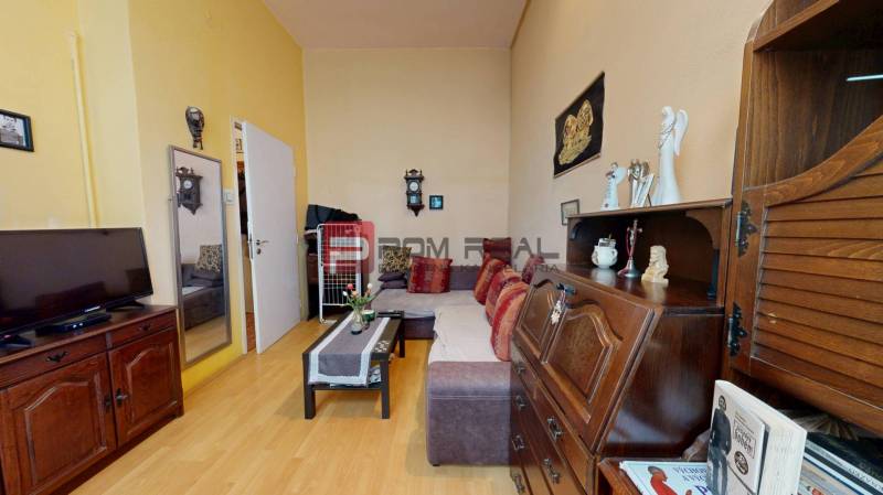 Living room in a two-room apartment with wooden furniture, a sofa, and a television.
