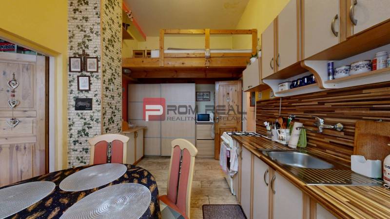 A kitchen with a dining table and a gallery in a 2-room apartment, wooden and brick decor.