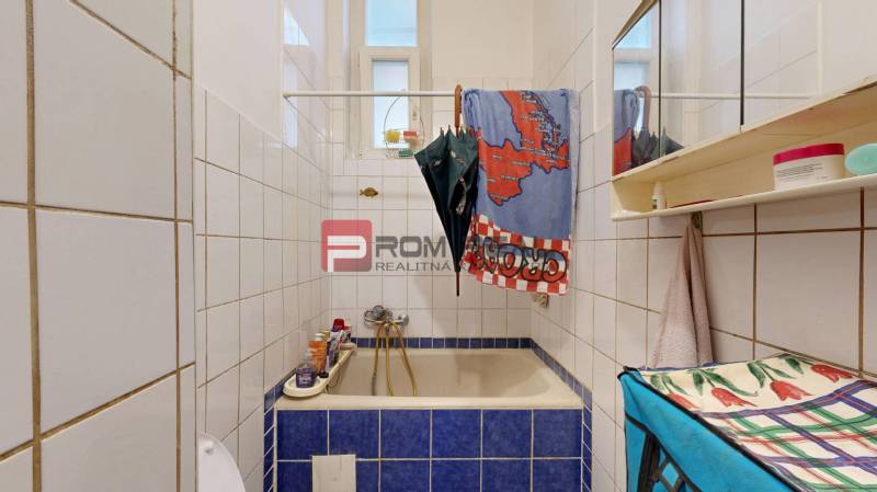 Bathroom with a bathtub and a mirrored cabinet in a 2-room apartment, white tiles, blue tiles.