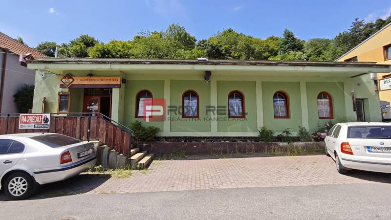 The building with white cars in the parking lot in the Gastro area at Podhradie in Svätý Jur.