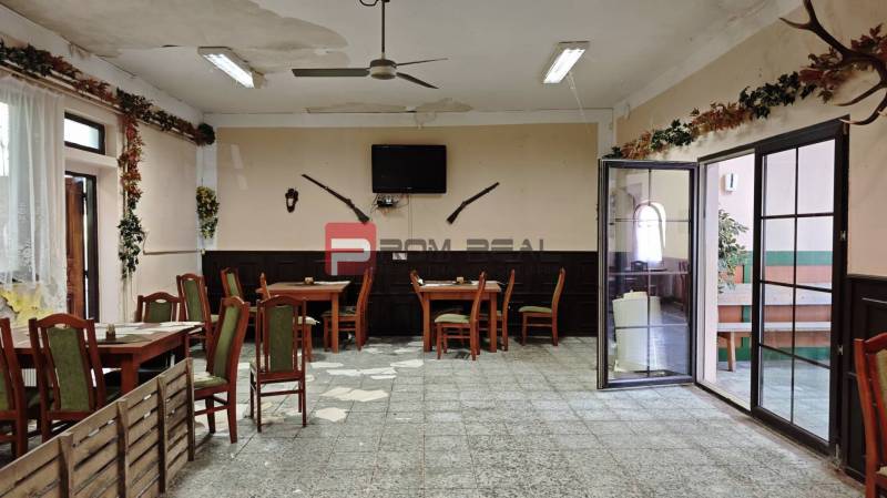 Interior of a gastro space with tables and chairs, decorations on the walls, and a TV.