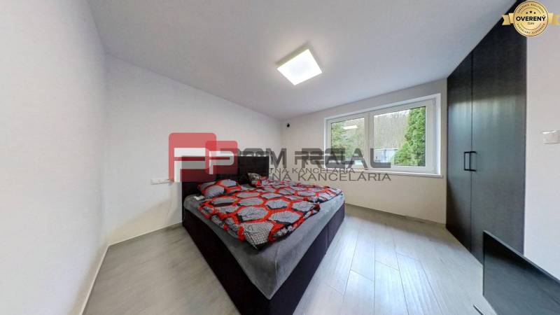 A bedroom in a family house with a double bed, dark furniture, and large windows.