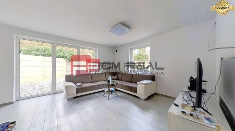 Living room in a family house with a sofa, windows, and a television.