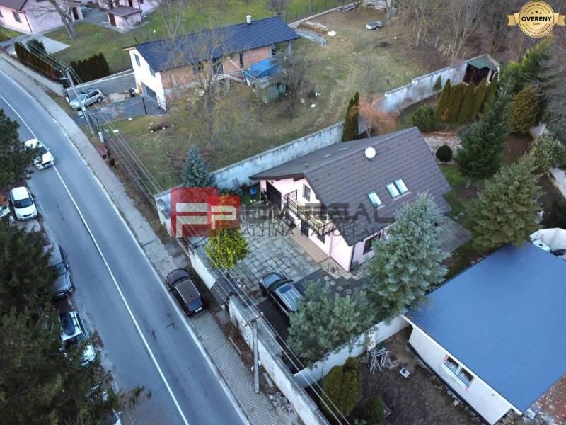 A family house in Píla by the road, with two cars and a landscaped garden.