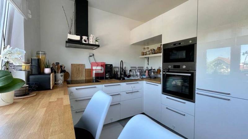 A kitchen in a 3-room apartment with white cabinets and a wooden countertop.