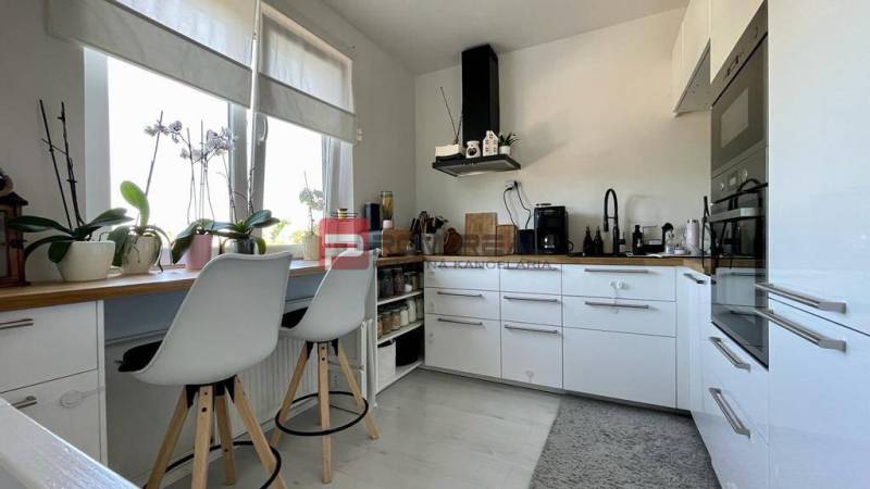 A kitchen in a 3-room apartment with white cabinets and bar stools.