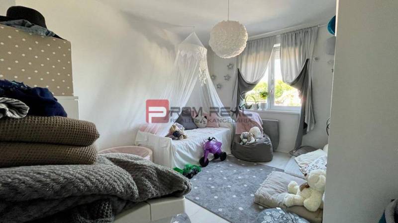 A children's room in a 3-room apartment with toys and a bed, with a view through the curtains.