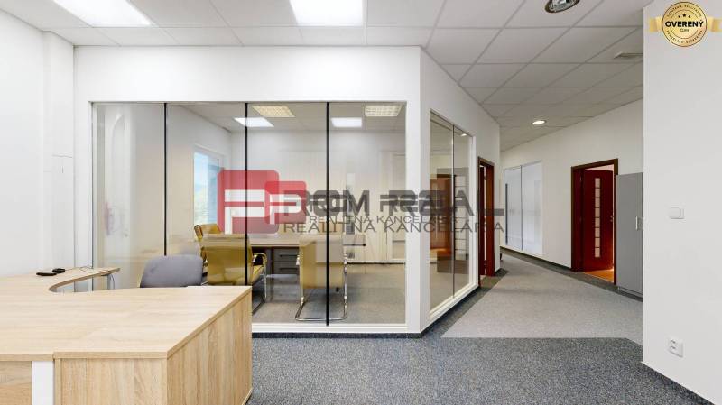 Offices with glass partitions, a wooden desk, and gray office chairs.