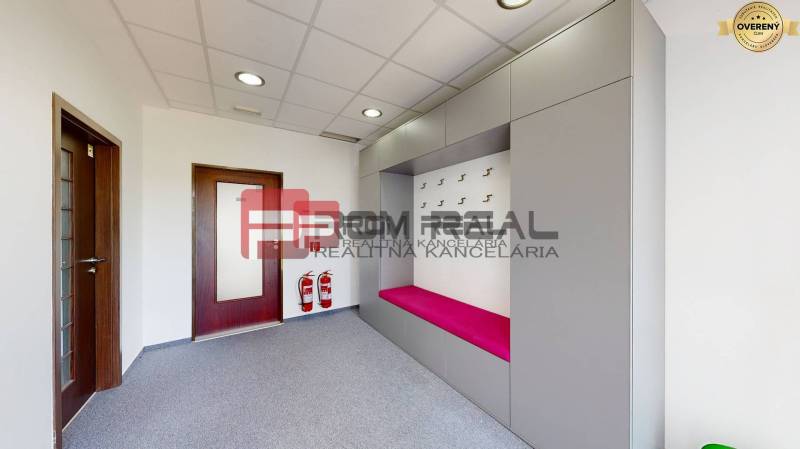 Interior of an office with a coat rack wall, a pink bench, and fire safety equipment.