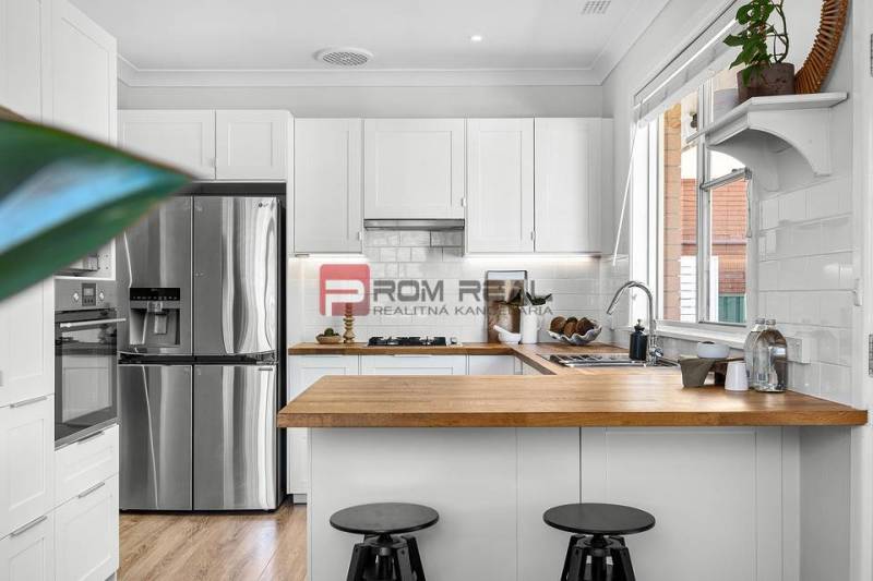 A kitchen in a 3-room apartment with a wooden countertop and a stainless steel refrigerator.