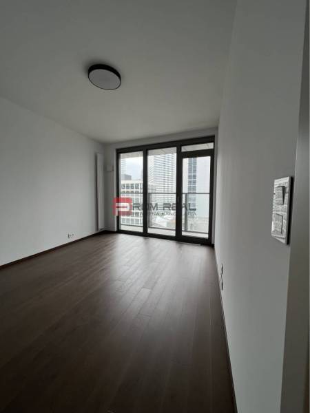 A spacious room with wooden flooring and large windows in commercial premises.