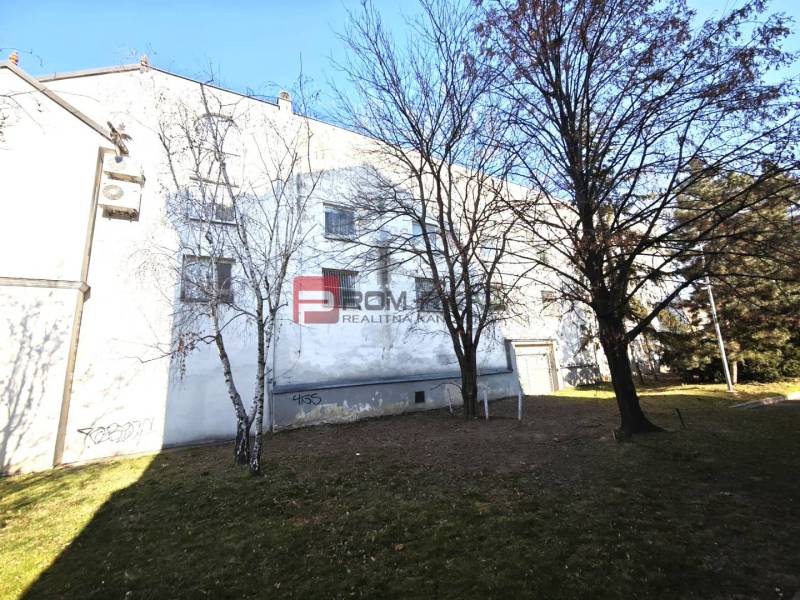 A building with greenery and trees on Ľ. Podjavorinská Street, with a blue sky in the background.