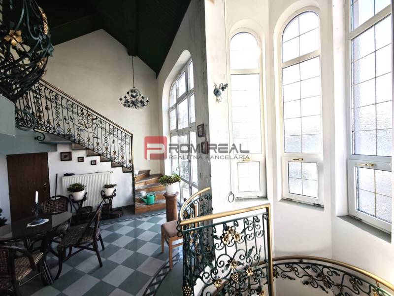 Interior of a building with a decorative staircase on Ľ. Podjavorinská Street, large windows letting in light.