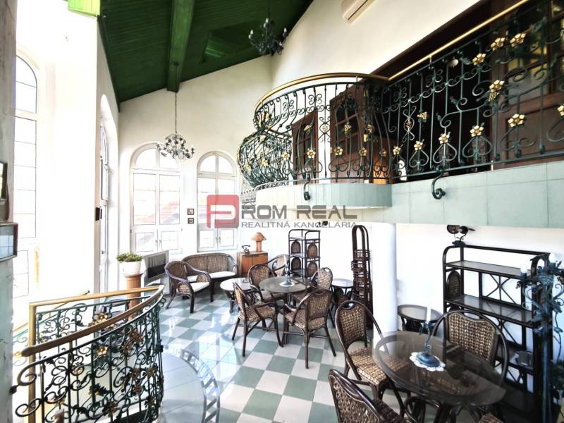 Interior of the building on Ľ. Podjavorinská Street with decorative railing, wrought iron chairs, and table.