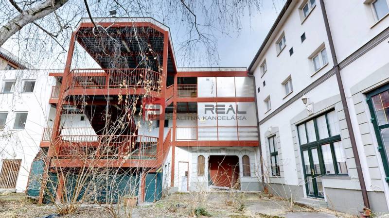 A building on Ľ. Podjavorinská Street in Trnava with an exterior metal staircase and glass windows.