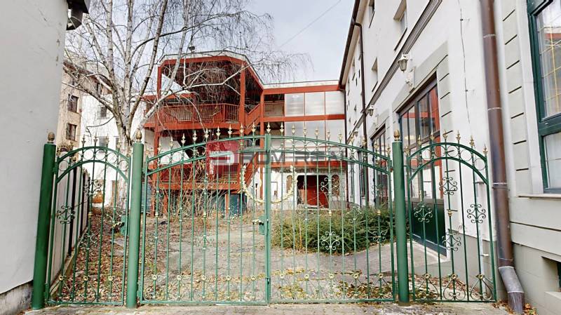 The garden in front of the building on Ľ. Podjavorinská Street in Trnava, with a green metal fence.