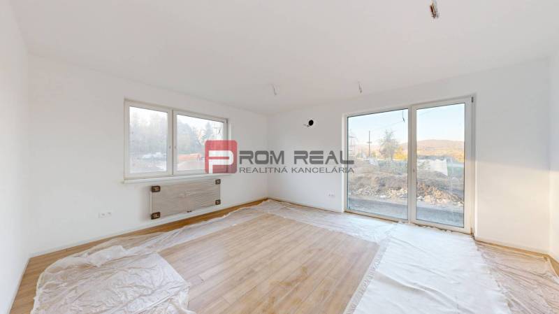 A room with a wooden floor and large windows provides brightness in the 2-room apartment.