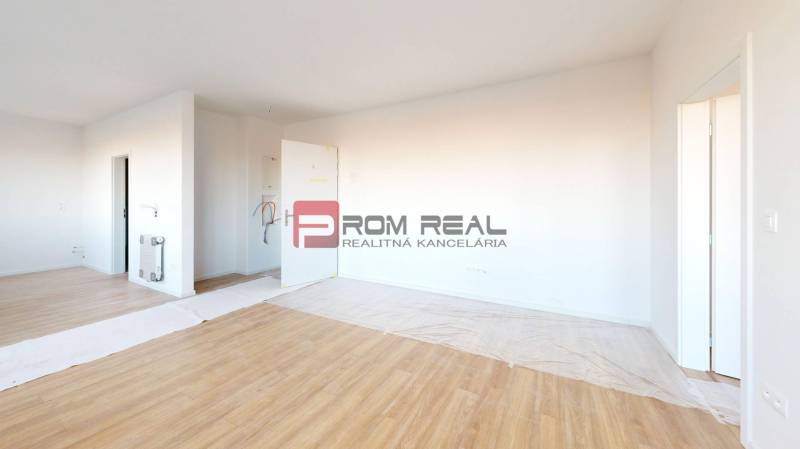 A spacious room in a 2-room apartment with laminate flooring and white walls.