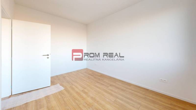 An empty room with wooden flooring and white walls in a 2-room apartment.