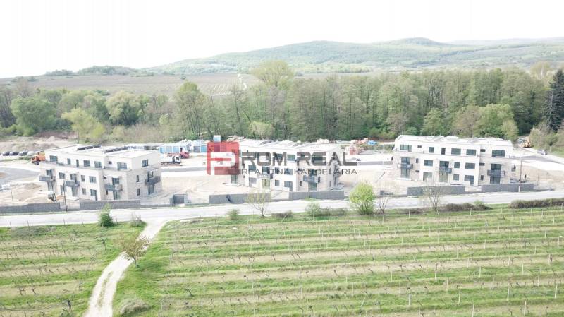 A new building on Limbašská Road in Pezinok, with vineyards and forests in the background.