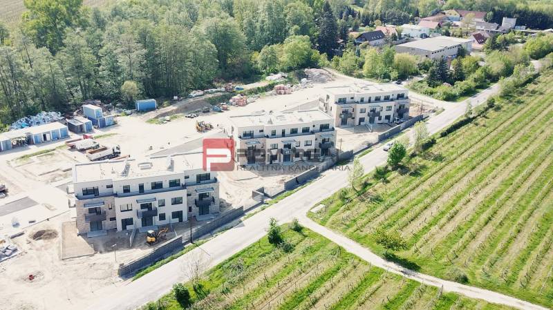 New buildings on Limbašská Road in Pezinok surrounded by greenery and unfinished spaces.