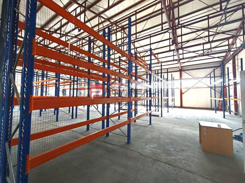 Shelves in the interior of warehouses and halls with window lighting and concrete flooring.