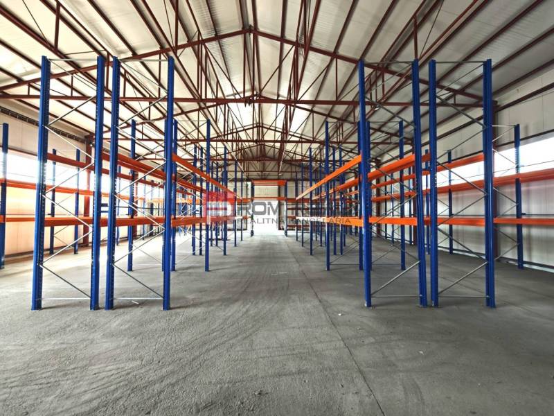 In warehouses and halls, there are metal racks with roof beams and concrete flooring.