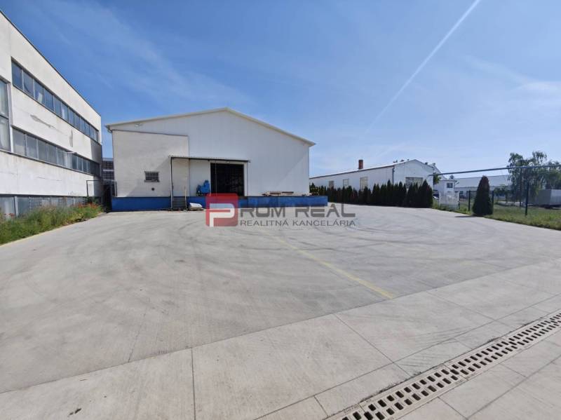 Warehouses and halls on Šúrska Street in Modra with a large concrete parking lot.