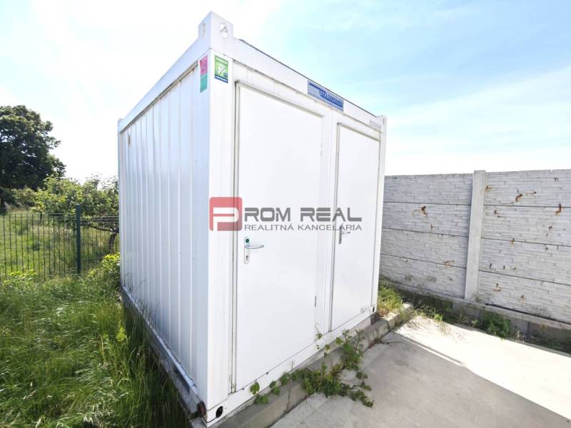 A white container on Šúrska Street in Modra, surrounded by greenery, warehouses, and halls.