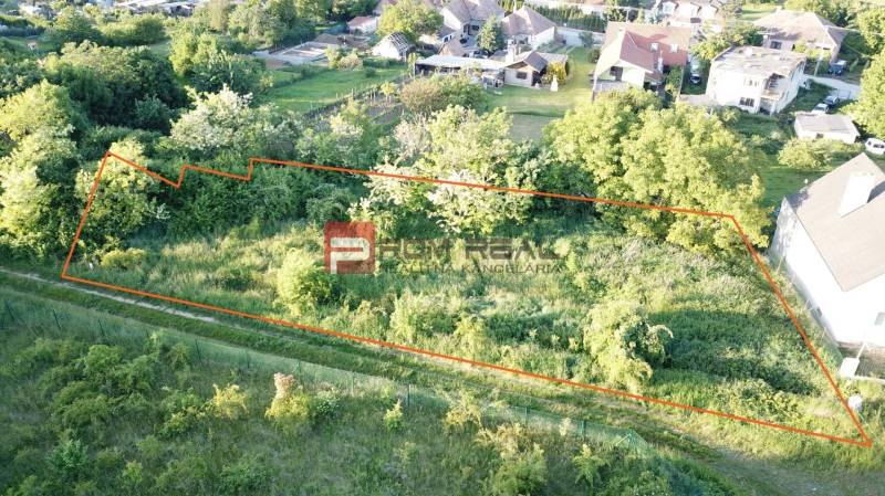 A plot for residential use on Poľná Street in Budmerice, surrounded by greenery and neighboring houses.