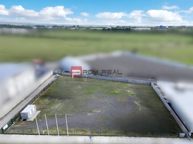 Production premises in Pezinok with an empty fenced plot and a container building.