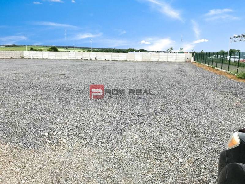 Gravel area in the production premises in Pezinok, bordered by a fence and a concrete wall.