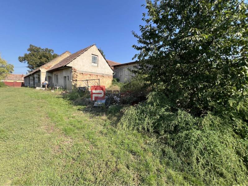 An older house surrounded by grass and vegetation on Main Street in Viničné, Land - residential.