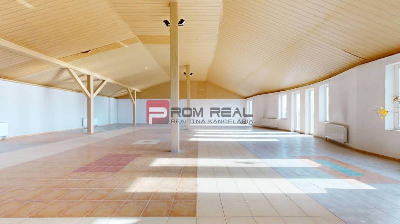 A spacious interior of a building with a wooden ceiling and light floor tiles.