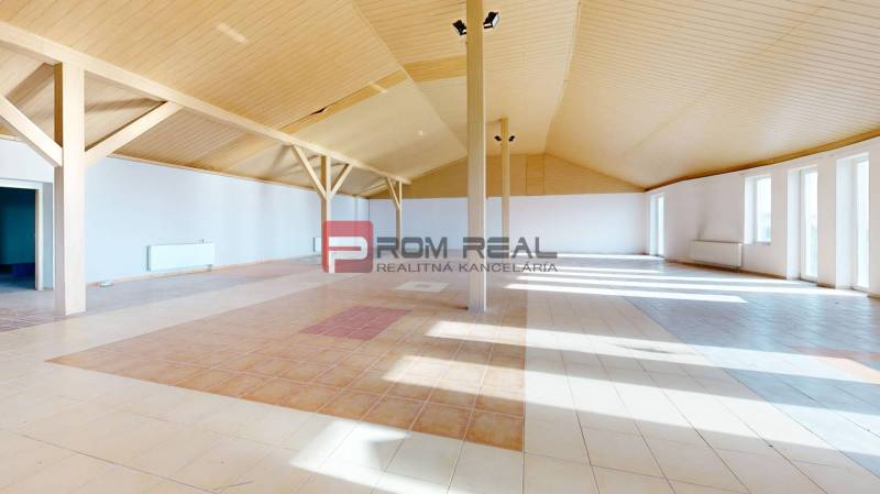 A spacious interior of a building with a patterned floor and a wooden ceiling.